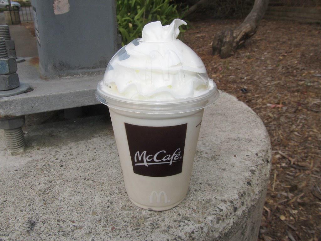 A classic McDonald's vanilla milkshake, served in a McDonald's branded cup with a red straw and topped with whipped cream